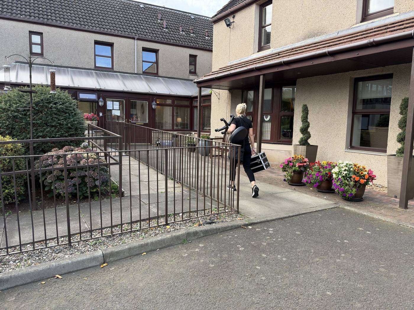 Jackie walking up to a care home entrance with her equipment